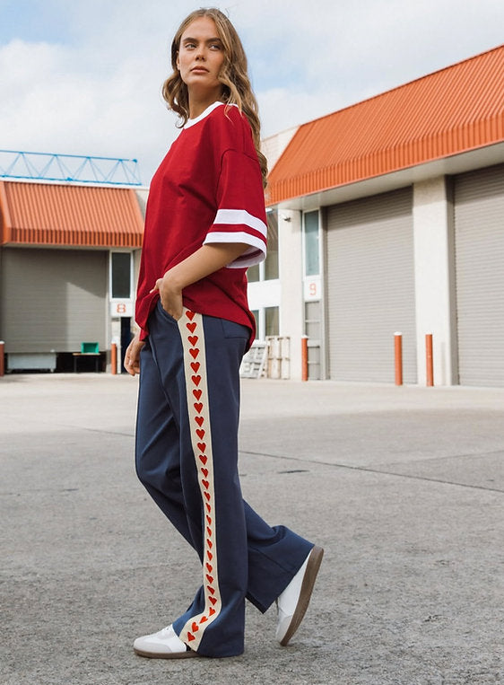 navy blue track pants with red heart stripes down the sides